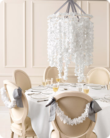 Nouveau Romantic Wedding Centerpiece made of white paper doilies suspended over a table and adorning the backs of wooden banquet chairs