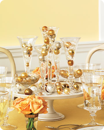 Glass flutes filled with small golden ornaments in various shades to mimic champagne bubbles