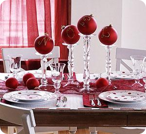 Large red ornaments stacked onto crystal candle holders atop of a red runners