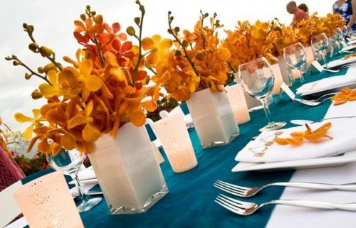 flame orange and red orchid centerpieces on estate tables 