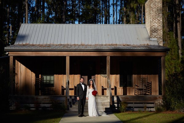 Elegantly dressed bride and groom on the porch of a rustic Savannah cabin