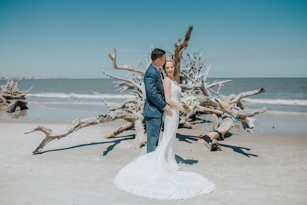 bride and groom in beach at Jekyll Island surrounded by driftwood
